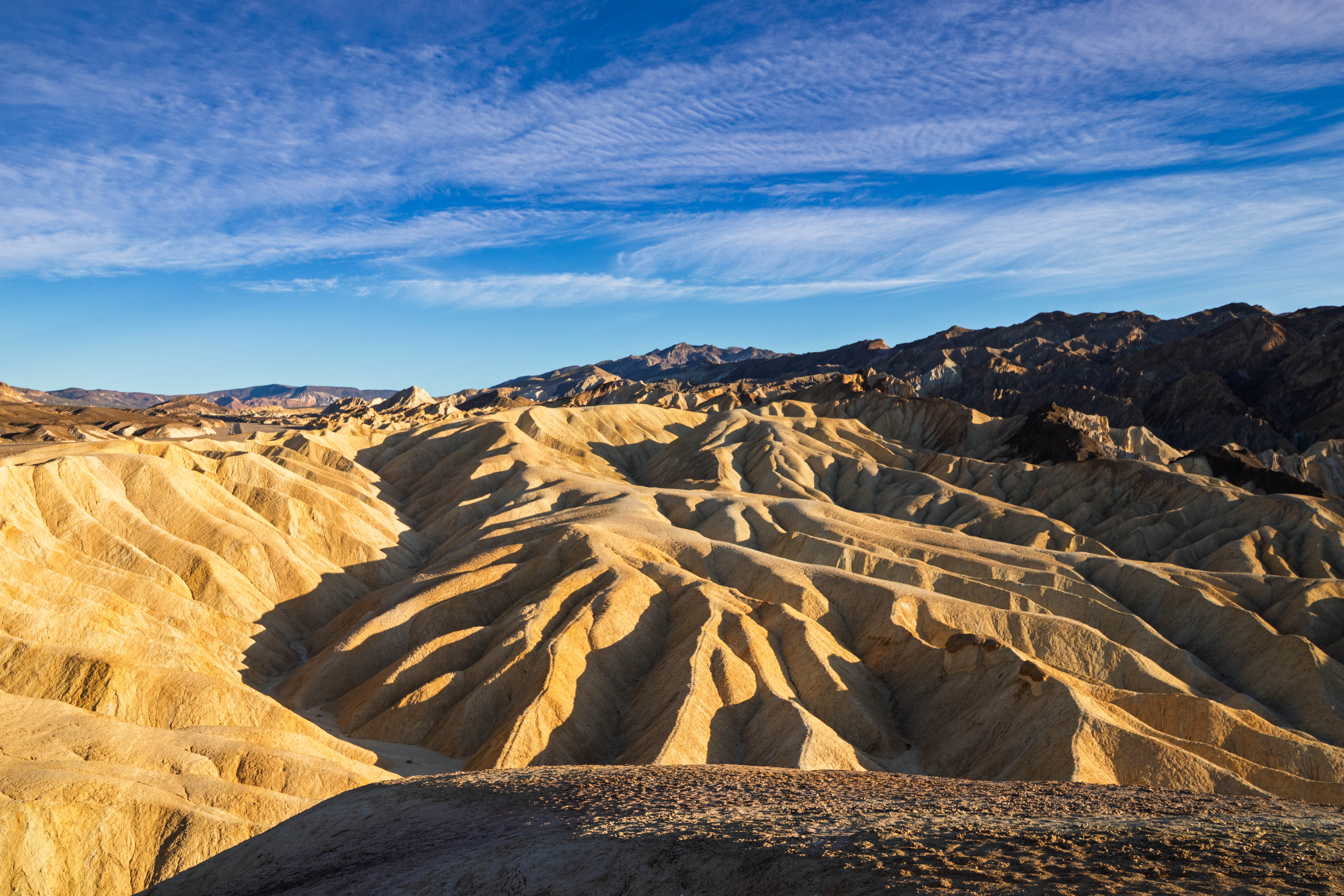 Death Valley badlands landscape under textured blue sky